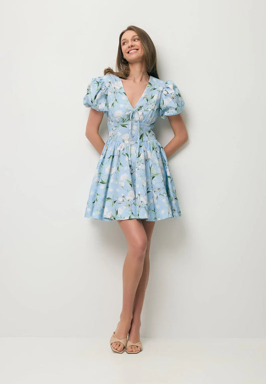 Uśmiechnięta modelka w mini sukience w niebieski kwiatowy print EVIANNE.