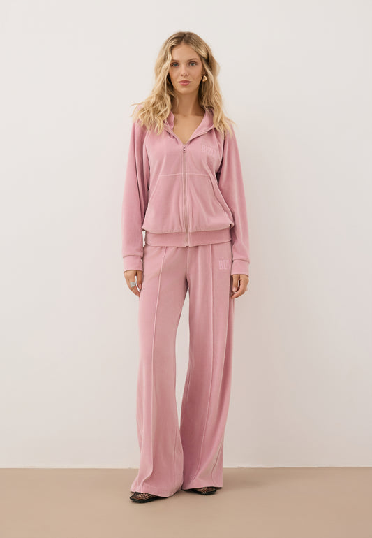 Modelka ubrana w różowy, welurowy dres - bluza IANELLA oraz spodnie VELORINA