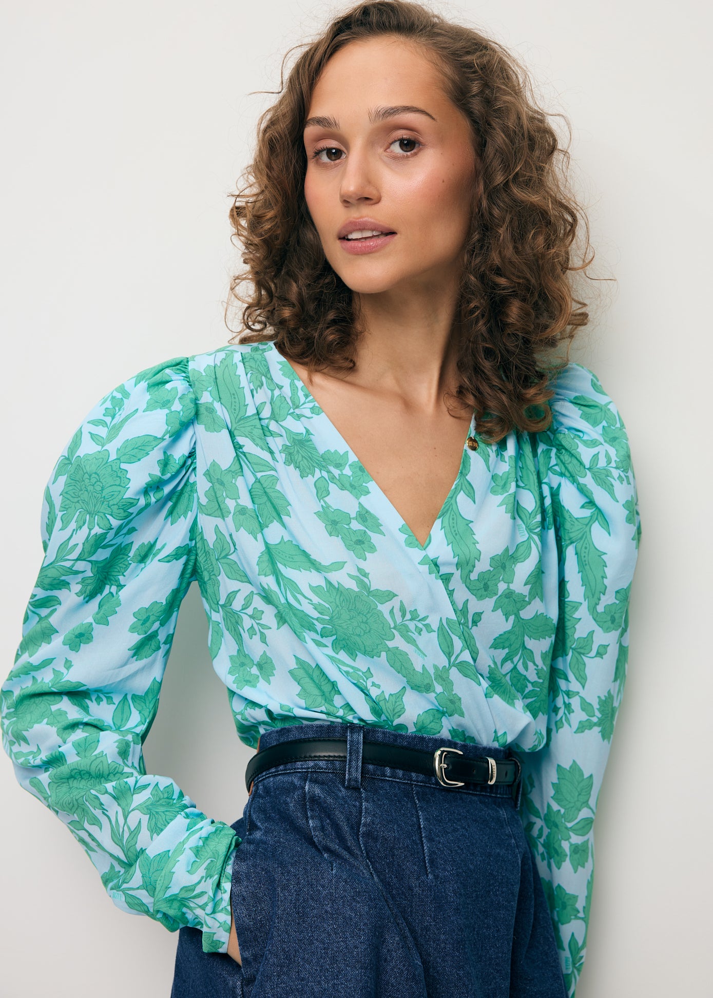 Zbliżenie na modelkę ubraną w niebieskie body w autorski print ALIBA oraz mini spódniczkę z jeansu BREDA.