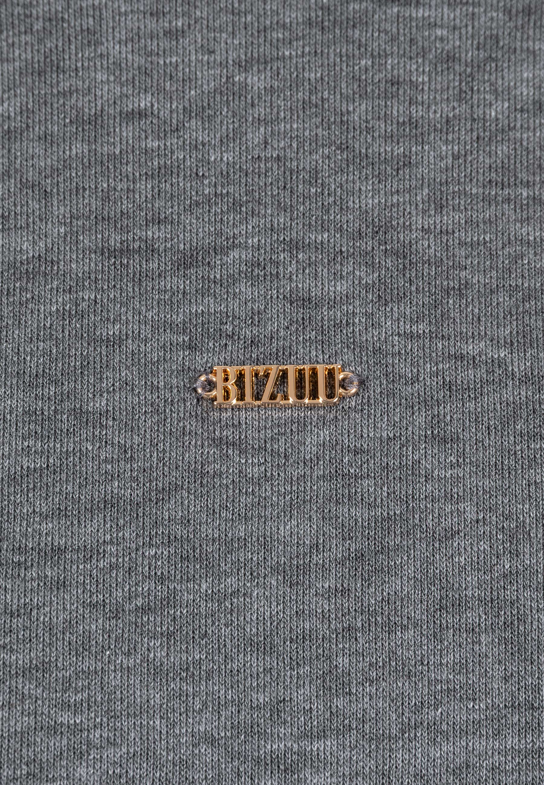 Zbliżenie na złote logo na przodzie dzianinowej sukienki CAGLIARI.