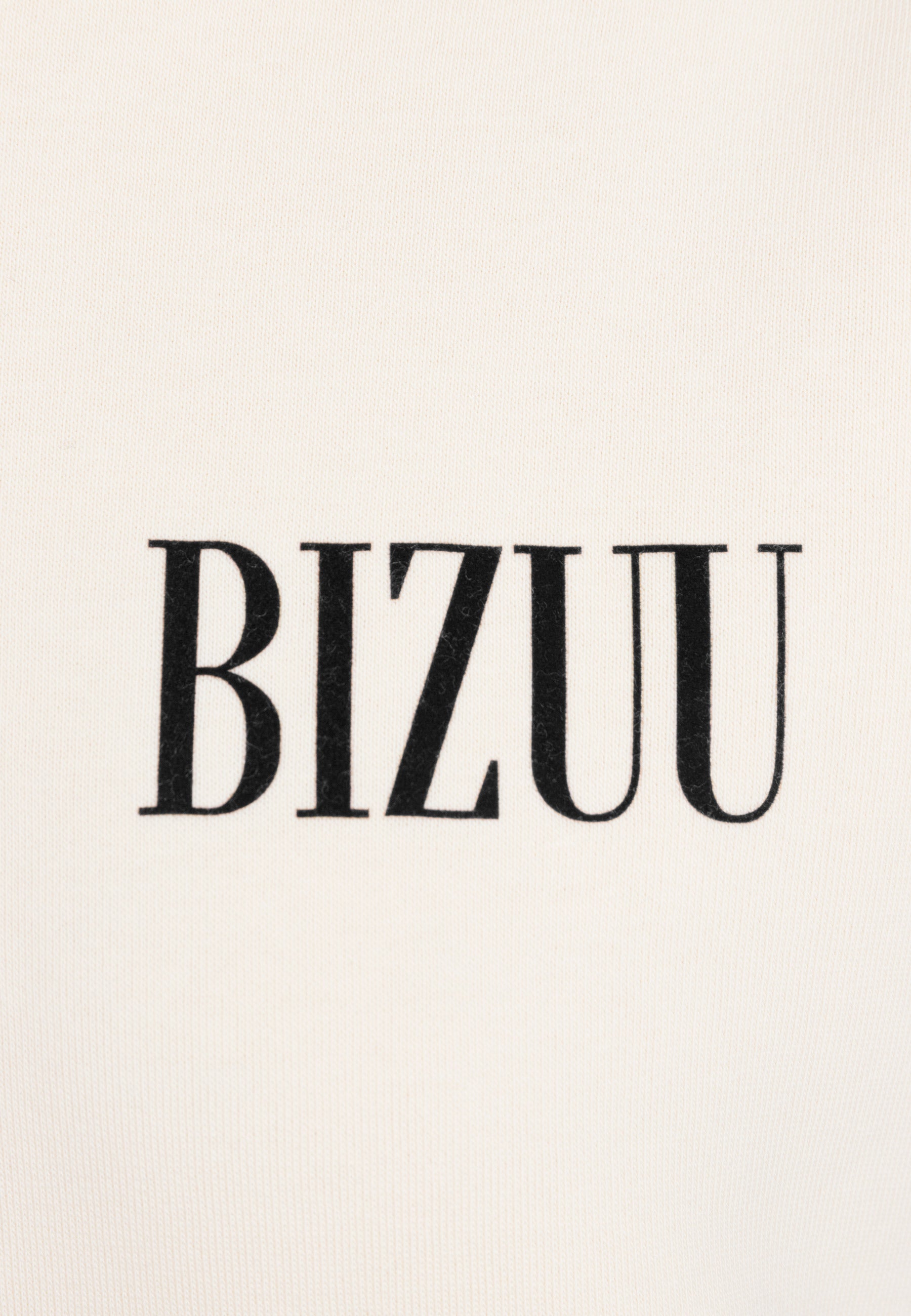 Zbliżenie na logo BIZUU na przodzie kremowej bluzy LINDI.