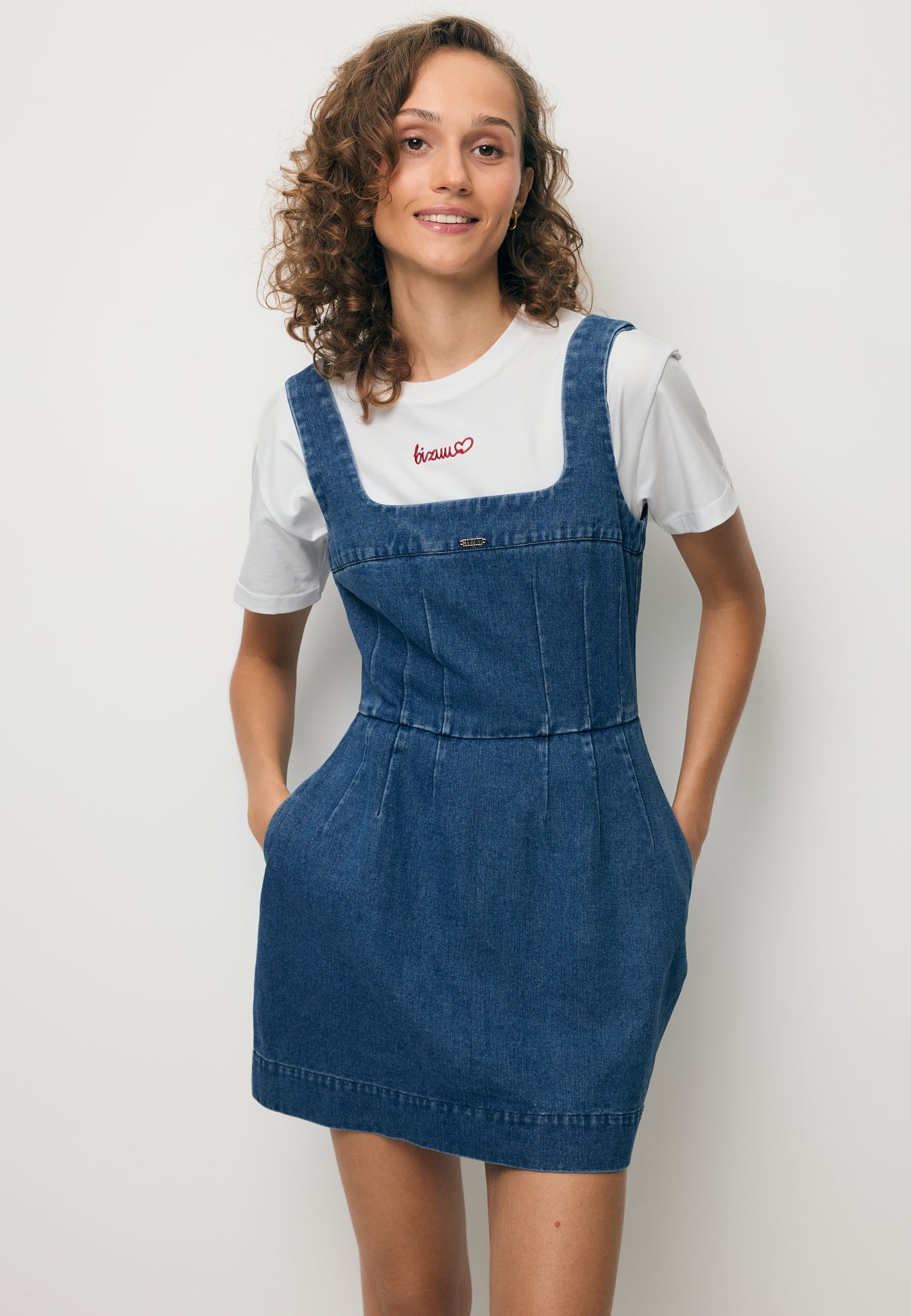 Modelka z rękoma w kieszeni mini sukienki jeansowej NARBONA