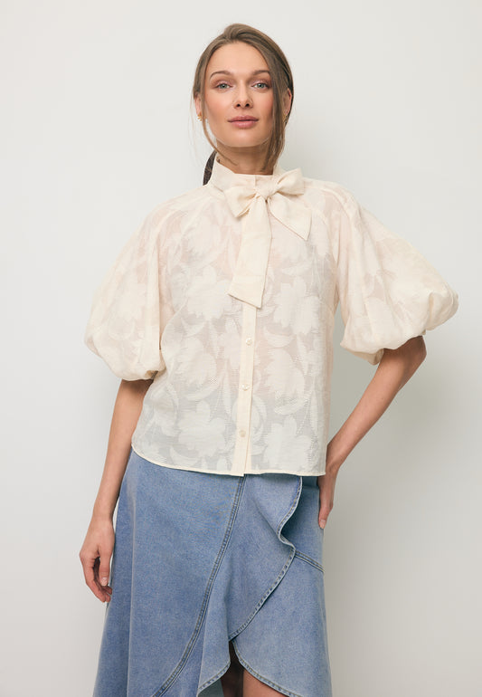 Zbliżenie na modelkę w kremowej koszuli w kwiatowy wzór AZALEA.