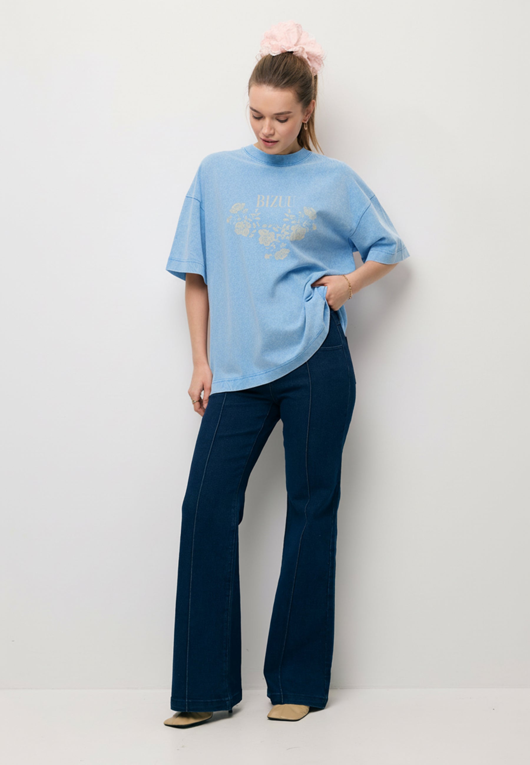 Modelka ubrana w błękitny T-shirt PAPLYS oraz granatowe jeansy.